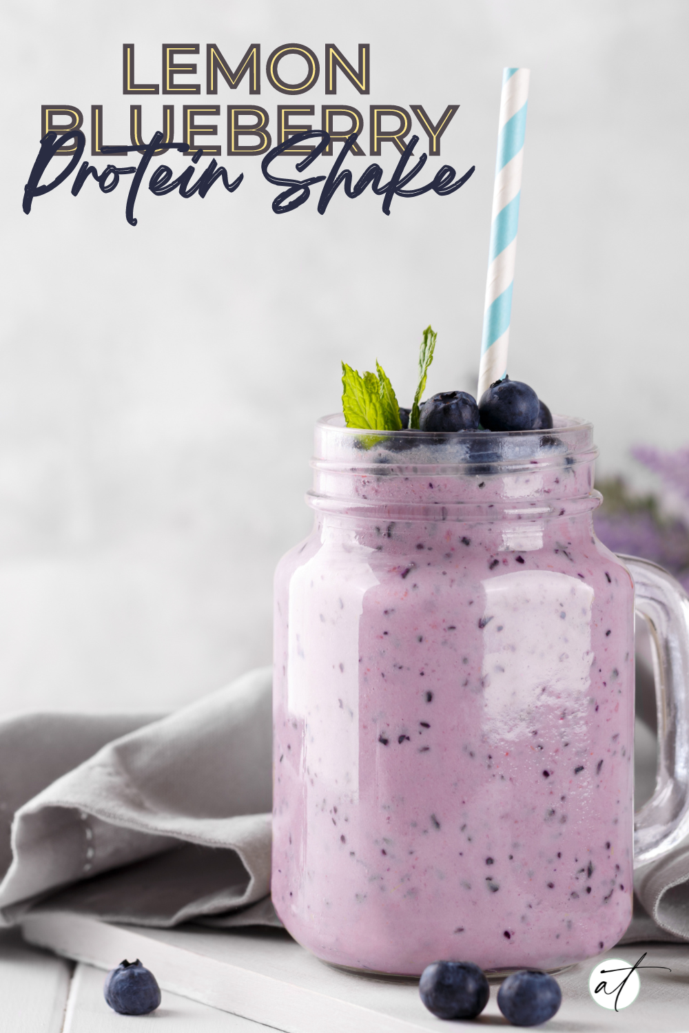 Photo of lemon blueberry protein shake in mason jar with a stripe straw - styled with fresh blueberries and lemon 