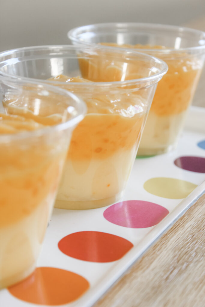 A prep photo of step two adding the orange layer of pudding to the yellow layer of pudding