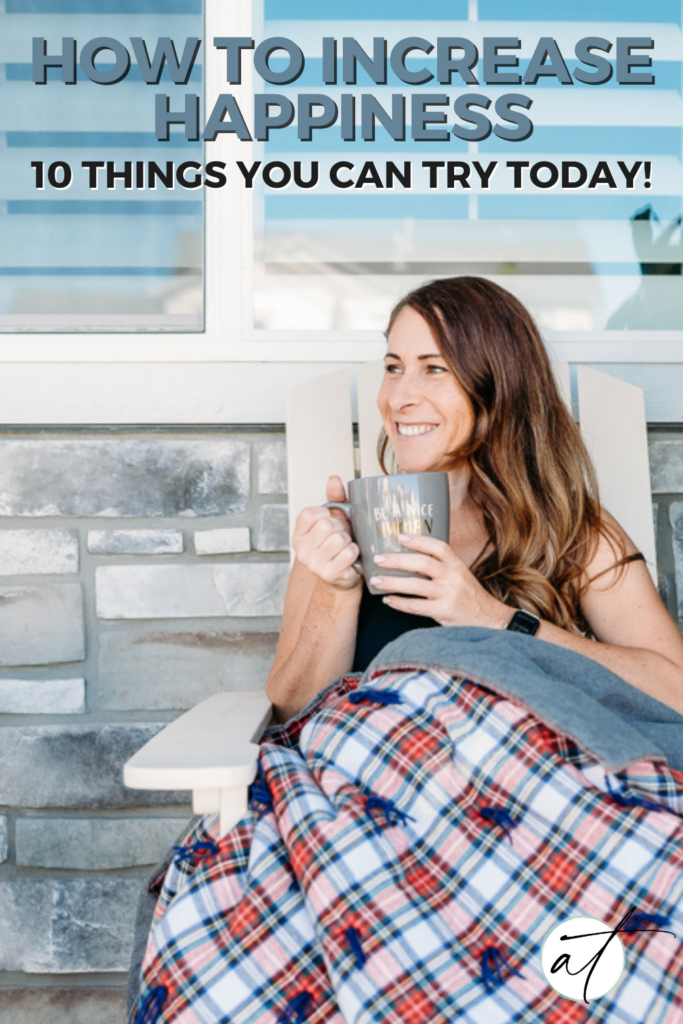 Photo of Andie on her front porch curled up with a plaid quilt drinking a hot beverage looking serene and happy. 