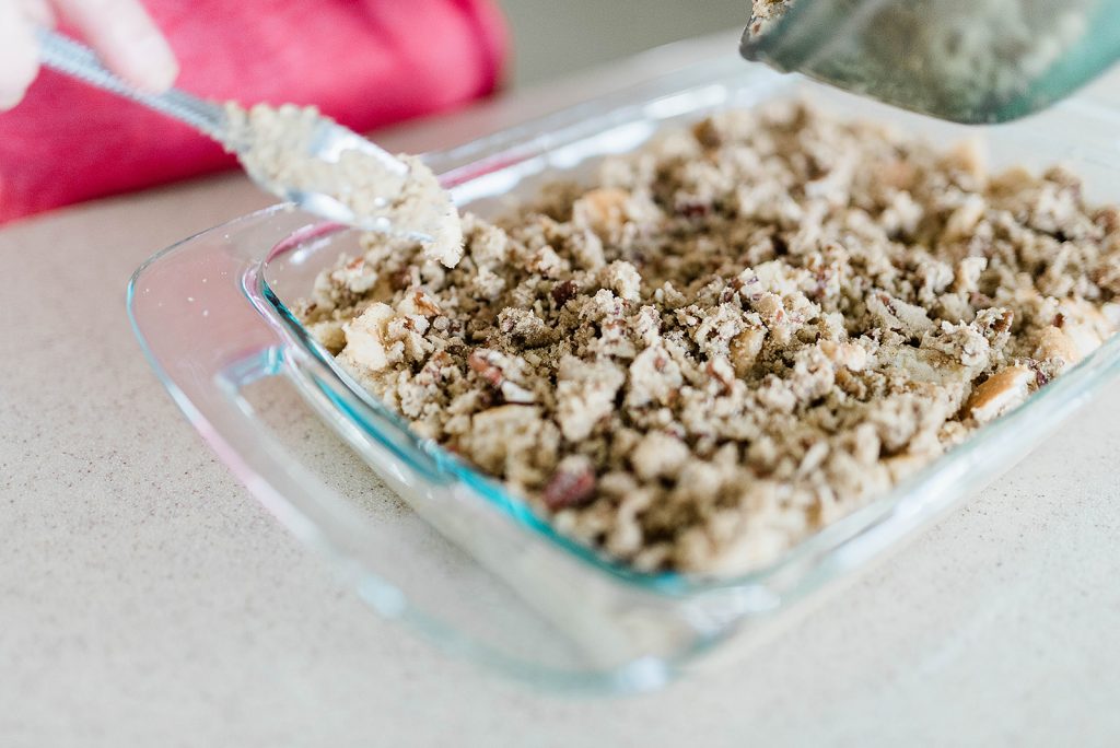Andie is placing the pecan mixture on to the top of the combined egg and bread mixture.