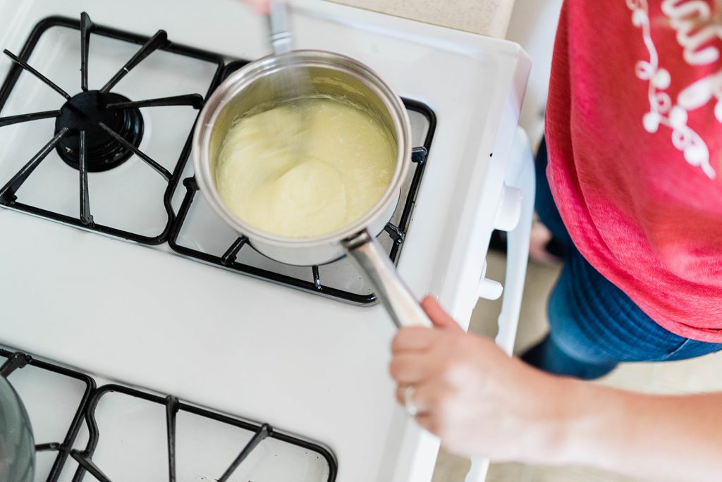 Andie is quickly whisking a raw egg into the warm bourbon sauce.