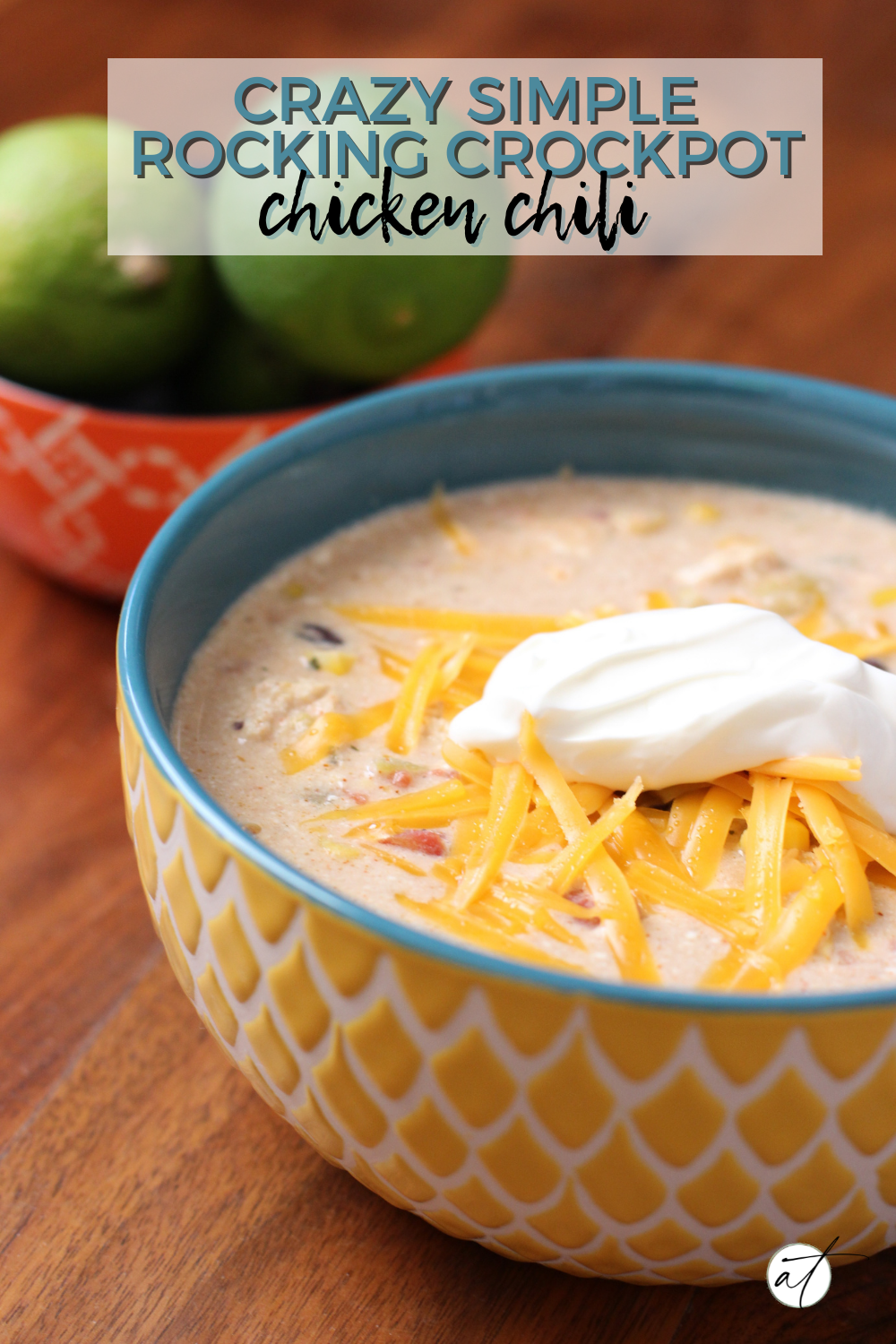 Photo of Crockpot Chicken Chili served in a large decorative bowl topped with shredded cheese and a dollop of sour cream.  