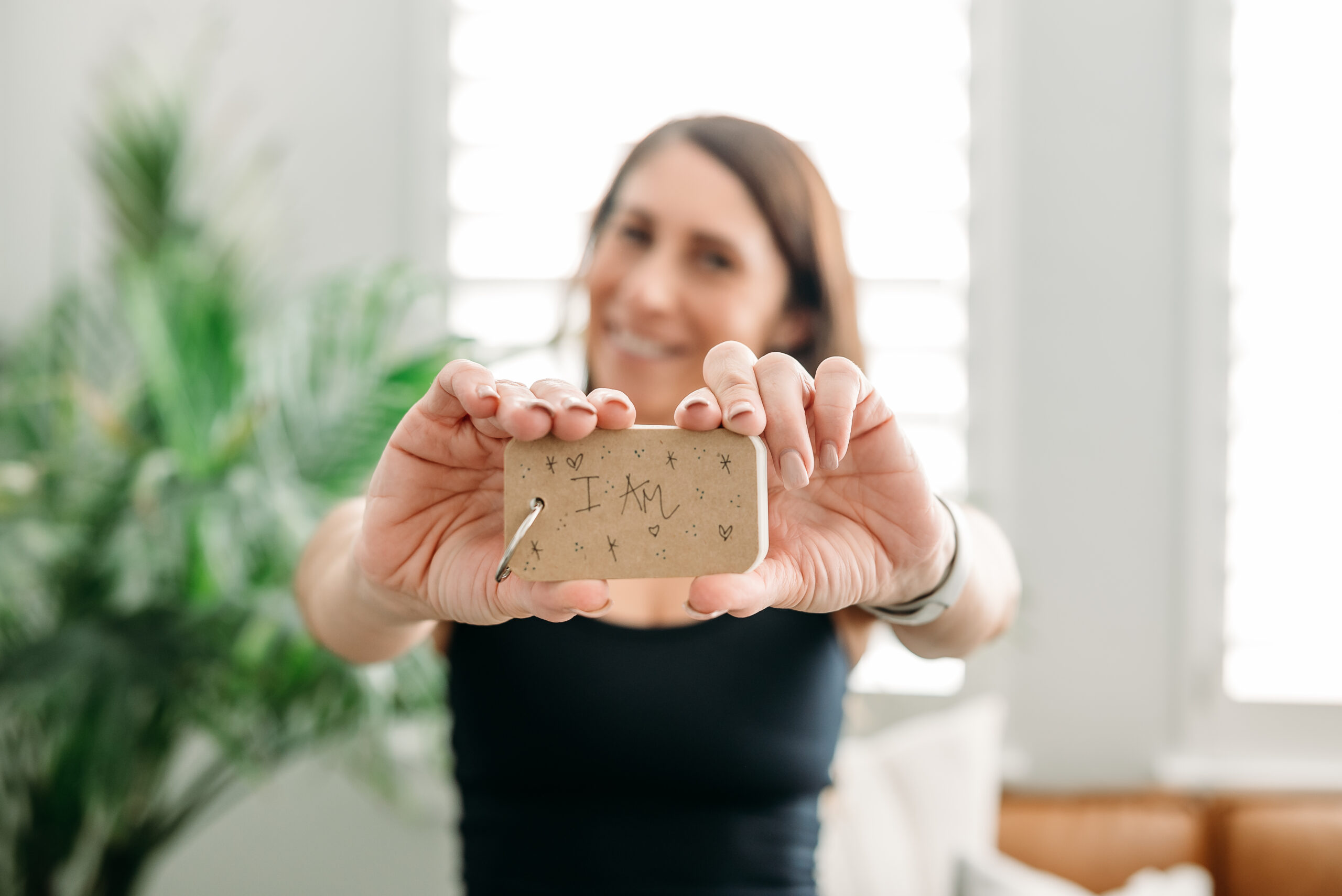 Photo of Andie holding I Am affirmations deck, a tool she uses to manifest in her own life. 