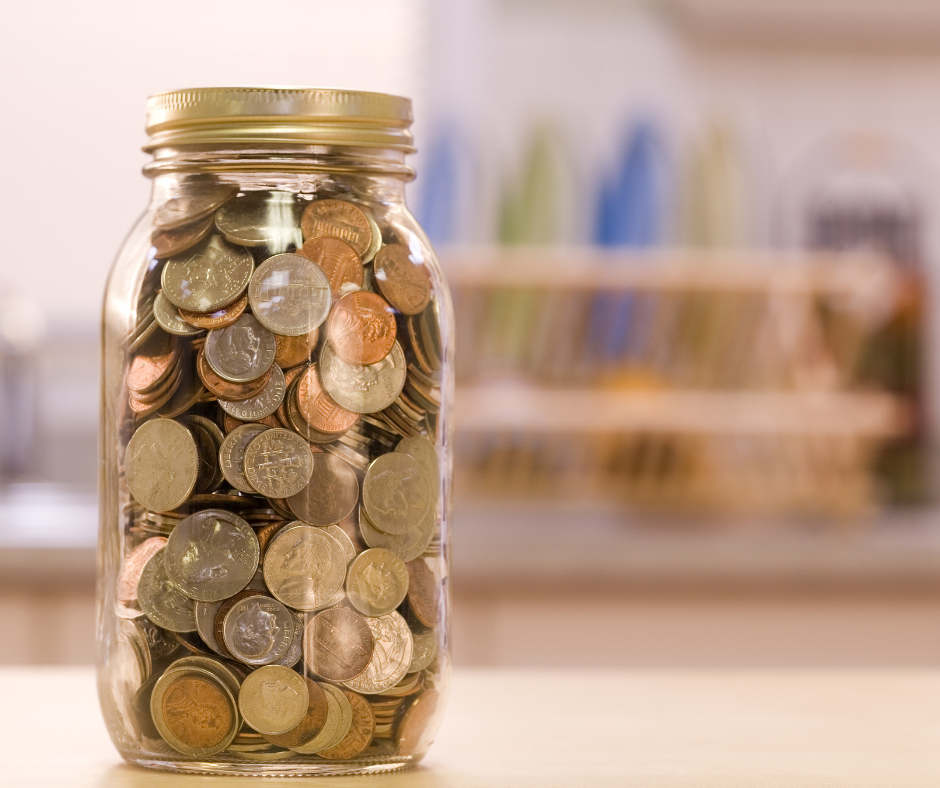 Image of a mason jar sitting on the counter, filled with loose change. Budget envelopes can be a great tool to help you save! 