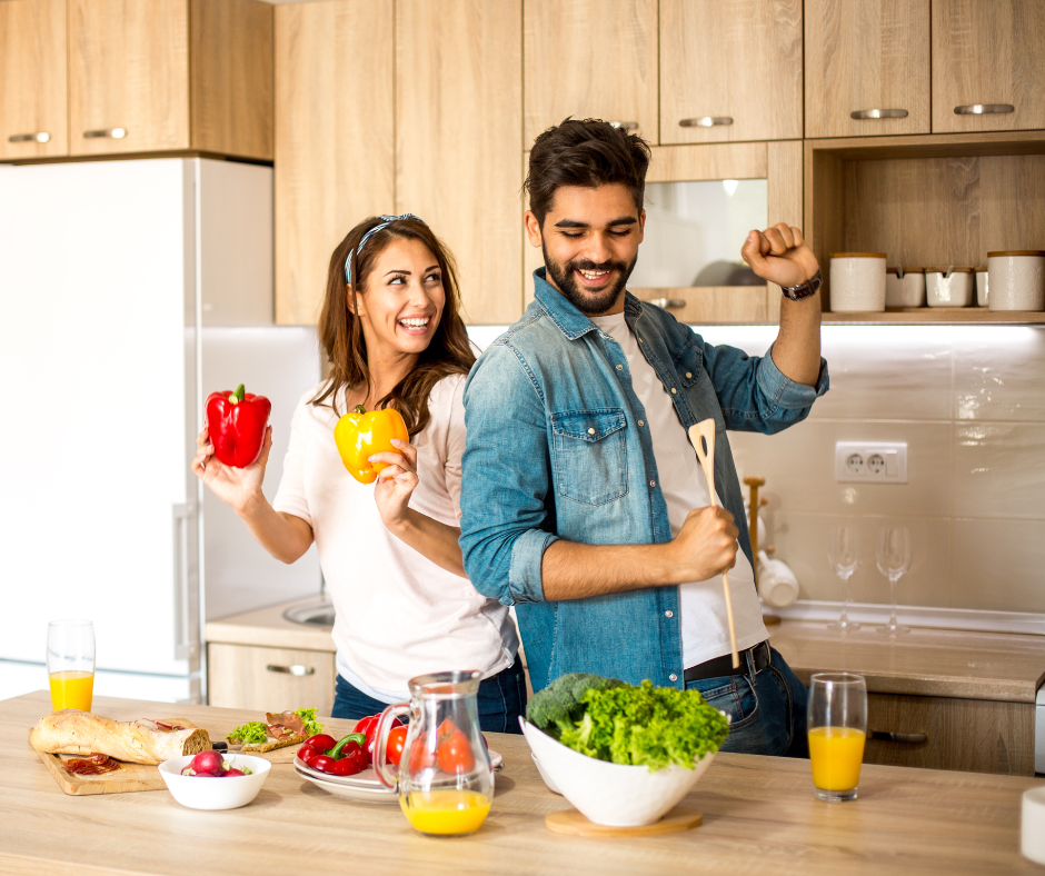 Photo of couple whipping up a healthy meal together as a team. Having fun getting healthy together is why this 30 day weight loss challenge works! 