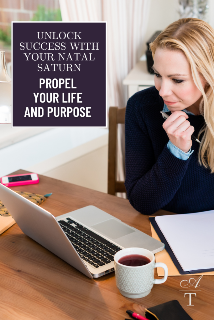 Photo of a blonde woman in a navy blue sweater working on her laptop while taking notes, there is a of tea nearby. The Photo has an overlay with the title of the blog post: Unlock Success with Your Natal Saturn: Propel Your Life and Purpose