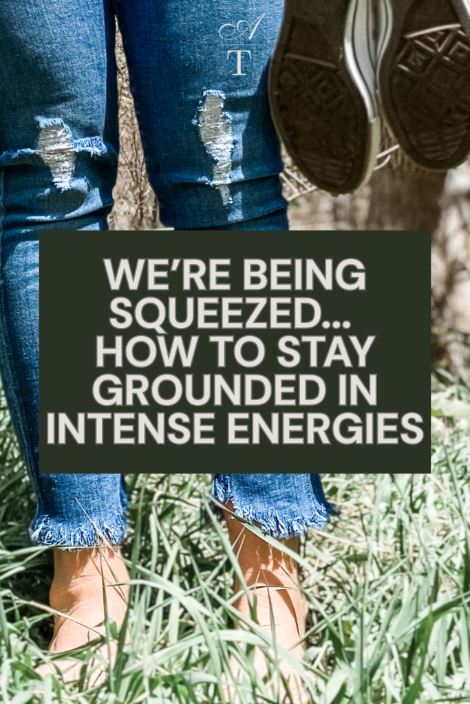 photo of Andie standing in the grass shoes off and in hand practicing grounding, answering the question on how to stay grounded in intense energies