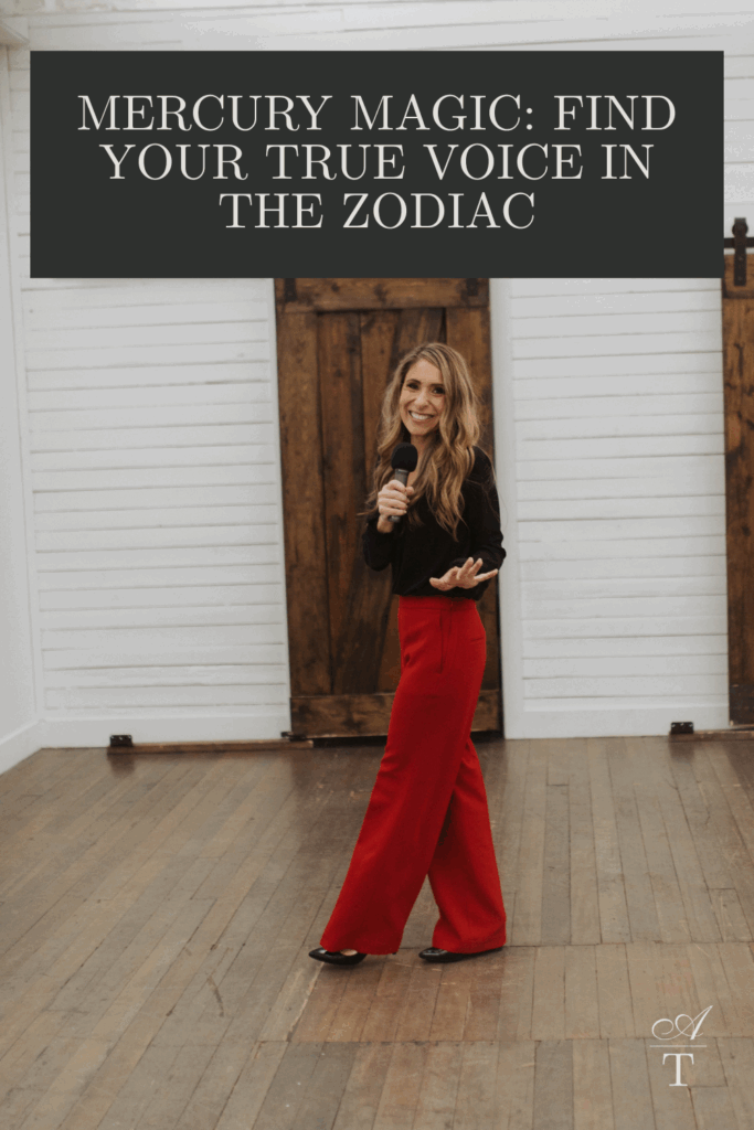 Photo of Andie walking with a mic, wearing a black top and red dress pants. The words "Mercury Magic: Find Your True Voice In The Zodiac" is written over the image. 